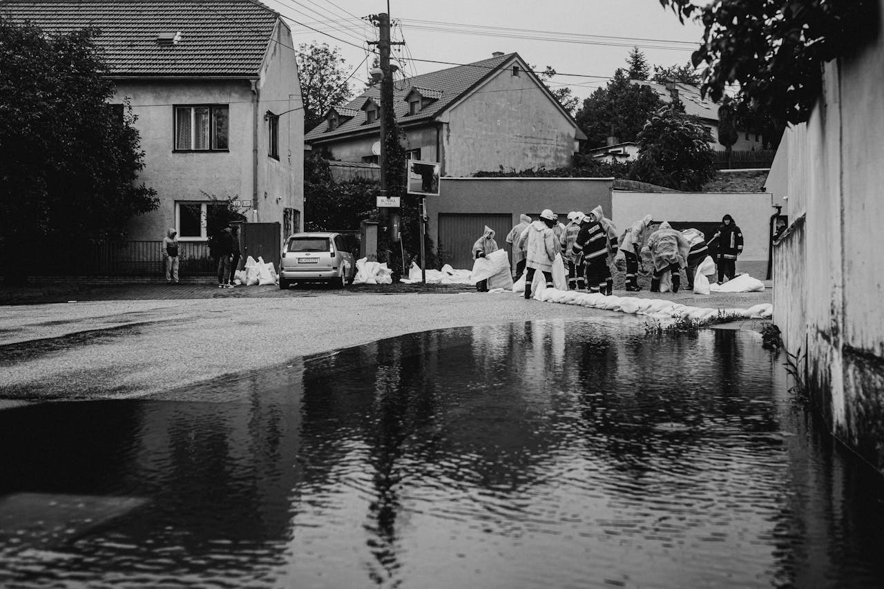 Volunteers in rain gear building sandbag barriers during urban flood.